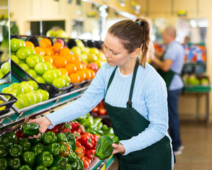 Wall Mural - woman seller offers buyer to choose ripe sweet pepper of green or red color