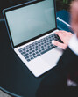 © BullRun - Person typing on modern laptop at black table in office