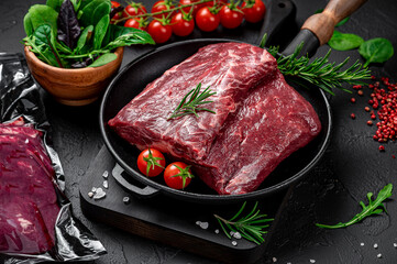 Wall Mural - Raw organic marbled beef with spices on a wooden cutting board on a black slate, stone or concrete background.