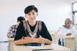© Gatot - Portrait of smiling asian male student sitting at desk in classroom at university
