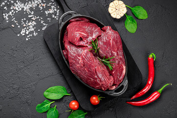 Wall Mural - Raw organic marbled beef with spices on a wooden cutting board on a black slate, stone or concrete background.