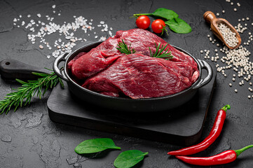 Wall Mural - Raw organic marbled beef with spices on a wooden cutting board on a black slate, stone or concrete background.