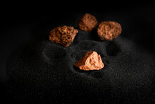 Lumps Of Pure Copper Or Pink Gold Ore On A Black Sand Background