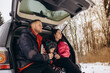 © Roman - Happy young family is traveling by car in winter forest. People have fun together. Mom, dad and children on winter walk.