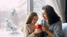 Mother And Daughter Enjoying Winter Nature In The  Window