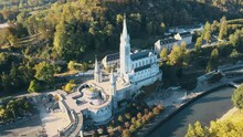 Aerial Tilting Establishing Shot Of The Lourdes Cathedral With Tourists Outside