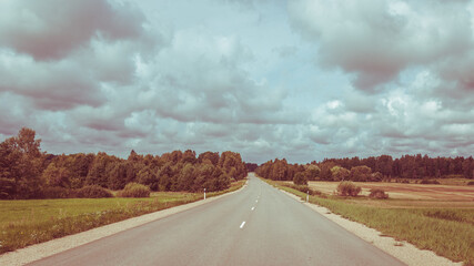 Rural landscape with asphalt road, fields and meadows- vintage photography look