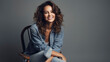 © LightoLife - Attractive young fashionable woman sitting on a chair against grey background with rocking denim and copyspace