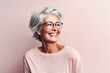 Portrait of attractive elderly happy laughing woman with gray hair wearing glasses over pink background. AI generated