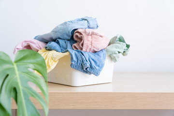 Wall Mural - Selection of fresh unfolded laundry in white basket on wood table