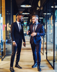 Wall Mural - Serious adult multiracial colleagues having conversation in light office corridor