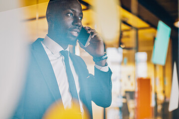 Wall Mural - Focused African American businessman speaking on smartphone in office