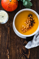 Wall Mural - Bowl with vegan pumpkin and chickpea cream soup  on wooden table, directly above