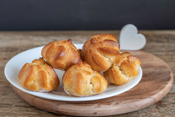 Wall Mural - Profiteroles or cream puff or choux pastry balls on wooden background.