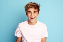 Handsome, Smiling Teen Boy With Stylish Hairstyle, In Casual White T-shirt Against Blue Studio Background. Human Emotions
