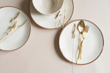 Fototapeta  - beige empty porcelain plate on pastel background with golden cutlery and dried flowers. Boho minimalist aesthetic. Dishware mock up.