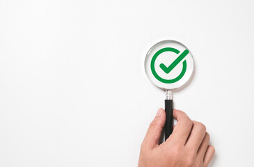 Fototapete - Hand holding magnifier glass with green correct sign or tick mark for document , project approve and accept verification code concept.