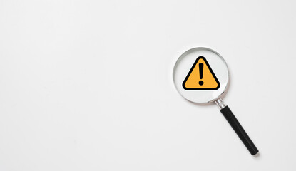 Black and yellow triangle caution warning sign inside of magnifier glass for notification error and maintenance concept.
