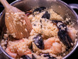 Preparation of creamy Italian seafood risotto with saffron rice in a pot with a wooden spoon.