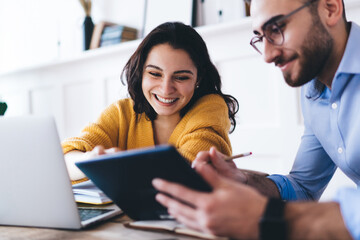 Happy couple taking notes and browsing gadgets