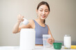 © Pormezz - Young sporty woman pouring protein powder into a cup to make replacement food meal after workout