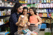 Beautiful Indian happy family of a mid aged mother and daughters shopping in a grocery store and supermarket. They are looking for desired products