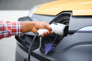 African American man charging his electric car.