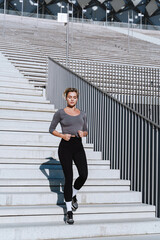 Wall Mural - Woman athlete wearing female sportswear running and  exercising on staircase between bleachers of outdoor stadium