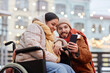 © Seventyfour - Portrait of young woman with disability taking selfie photo outdoors with boyfriend and using smartphone