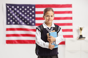 Wall Mural - Female pupil holding books and posing in front of USA flag