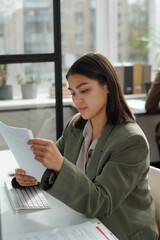 Poster - Young female secretary in formalwear looking through financial papers while preparing documents for negotiation and making business deal