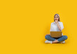 © Designerant - Blonde girl pondering over a problem, full body view caucasian blonde girl pondering over a problem. Sit floor legs crossed hold laptop touching chin  with hand looking aside copy space. Pensive.