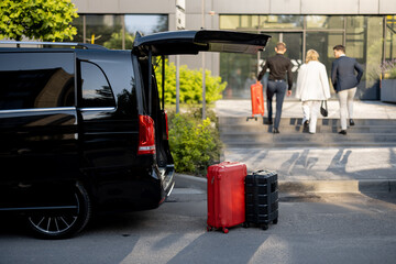 Wall Mural - Driver or concierge helps a business couple carry their suitcases to the office or hotel from a minivan taxi. Concept of business travel and transportation service