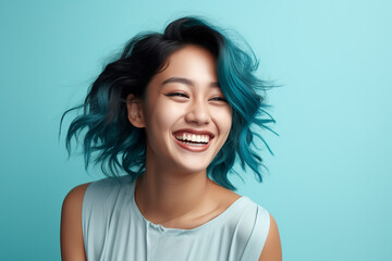 Wall Mural - Laughing Asian woman with blue hair in front of light blue background