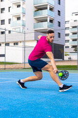 Wall Mural - Young adult man playing Pickleball. Portrait of a man performing a backhand shot in a pickleball match