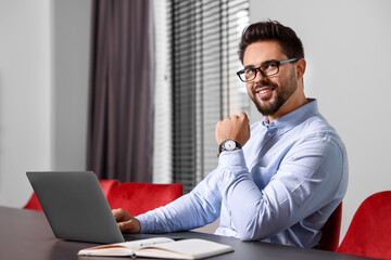 Sticker - Happy young man working on laptop at table in office