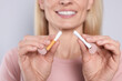 Woman with broken cigarette on light grey background, closeup. Stop smoking concept