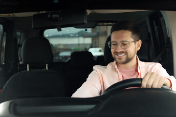 Wall Mural - Listening to radio. Handsome man enjoying music in car, view through windshield