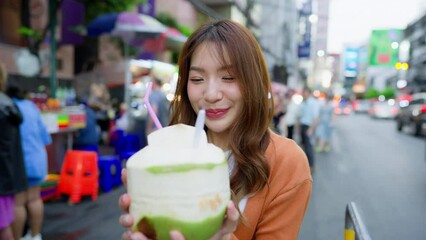 Wall Mural - Young asian woman traveller standing and drinking coconut water. Beauty traveller female in city lifestyle chinatown street food market Bangkok, Thailand