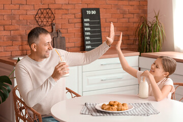 Canvas Print - Little girl with her father drinking milk and giving each other high-five in kitchen