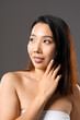 © Pixel-Shot - Beautiful Asian woman with cosmetic cream on her face against grey background