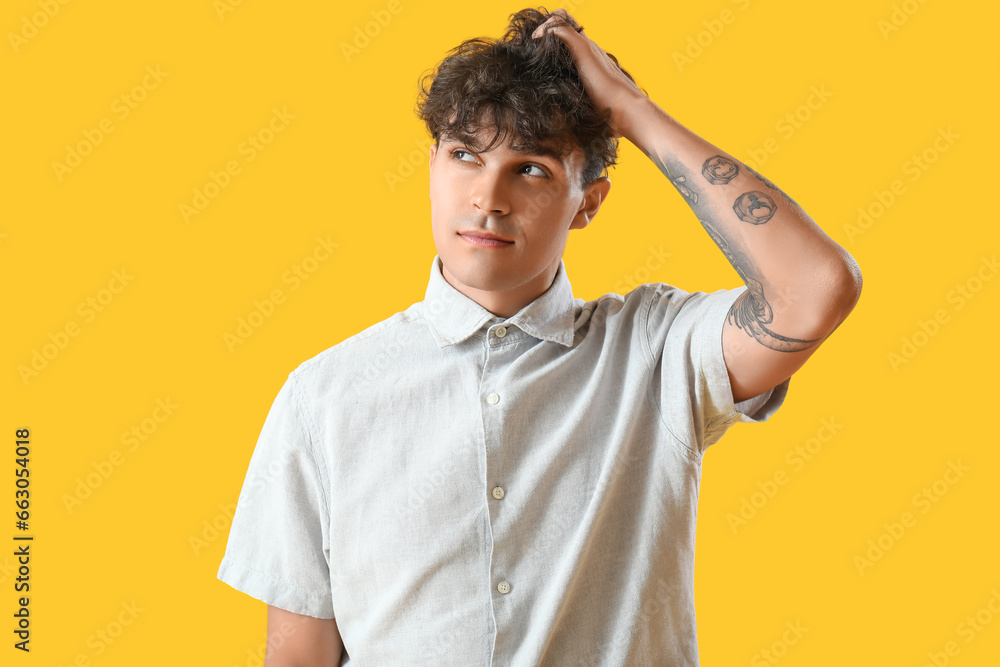 Portrait of handsome young man scratching his head on orange background