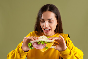 Wall Mural - Female student with tasty sandwich on green background