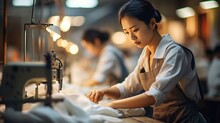 Asian Factory Workers Diligently Sewing Garments In A Bustling, Large-scale Production Setting.