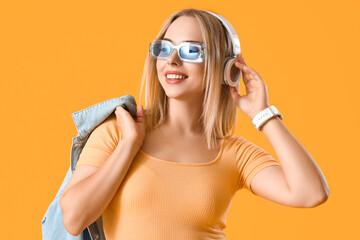 Sticker - Beautiful young stylish woman in headphones on yellow background