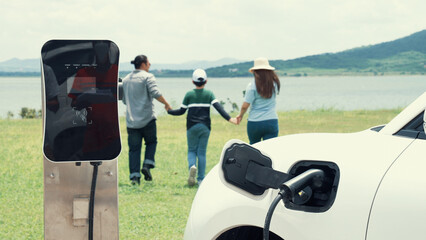 Sticker - Concept of progressive happy family enjoying their time at wind farm with electric vehicle. Electric vehicle driven by clean renewable energy from wind turbine generator for charging station.