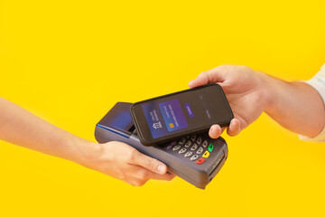 Poster - Man with mobile banking paying via terminal on yellow background, closeup