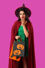 Canvas Print - Surprised young woman dressed for Halloween as witch with gift bags on purple background