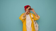 Portrait Of A Young Asian Man Wearing Yellow Jacket And Red Hat With Camera On Blue Background