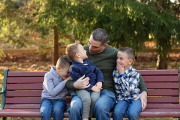 Father on a bench, engaged in a heartwarming interaction with his sons